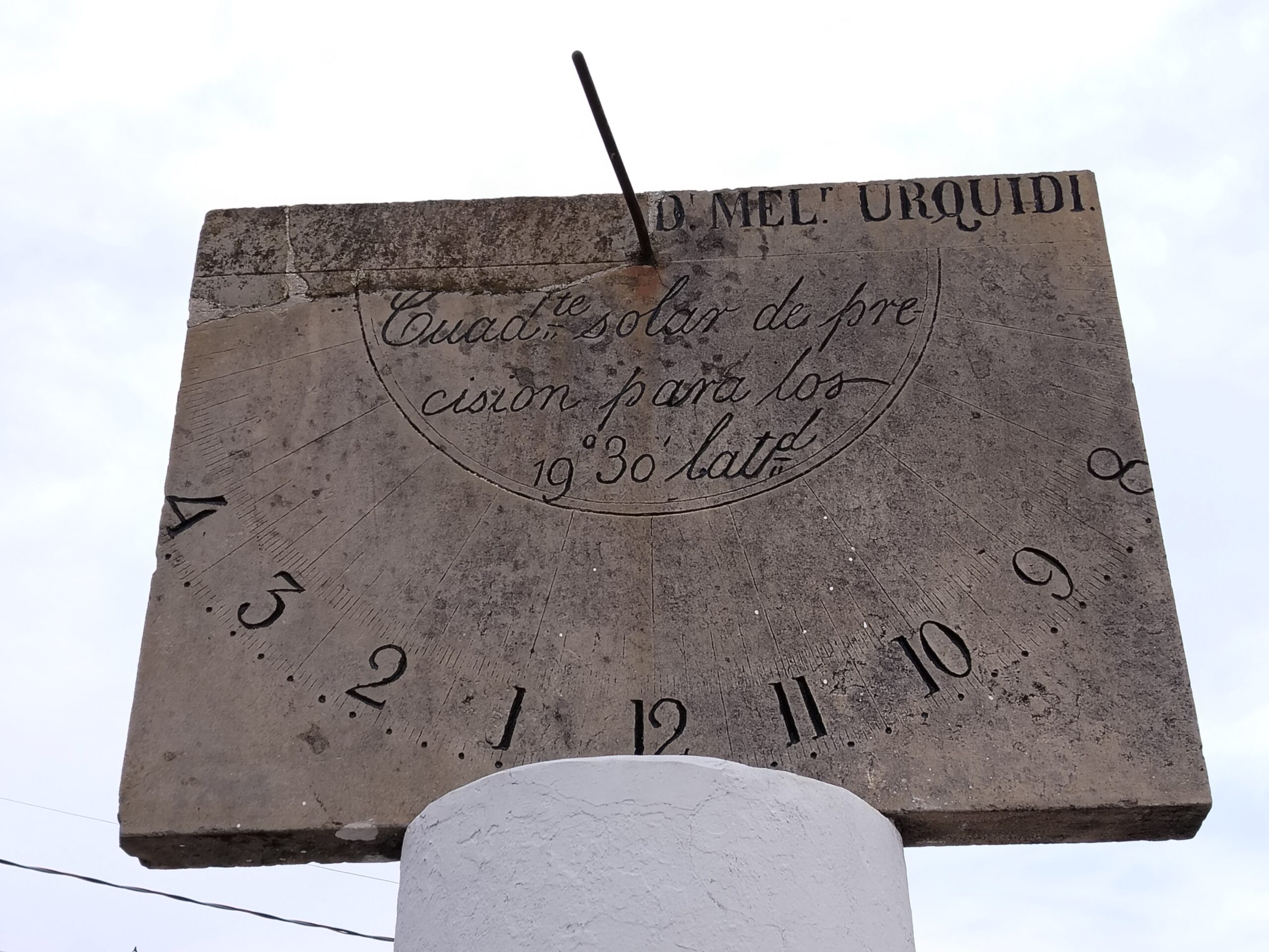 Vista cercana del reloj de sol sobre pedestal de piedra en la plaza de Recoleta