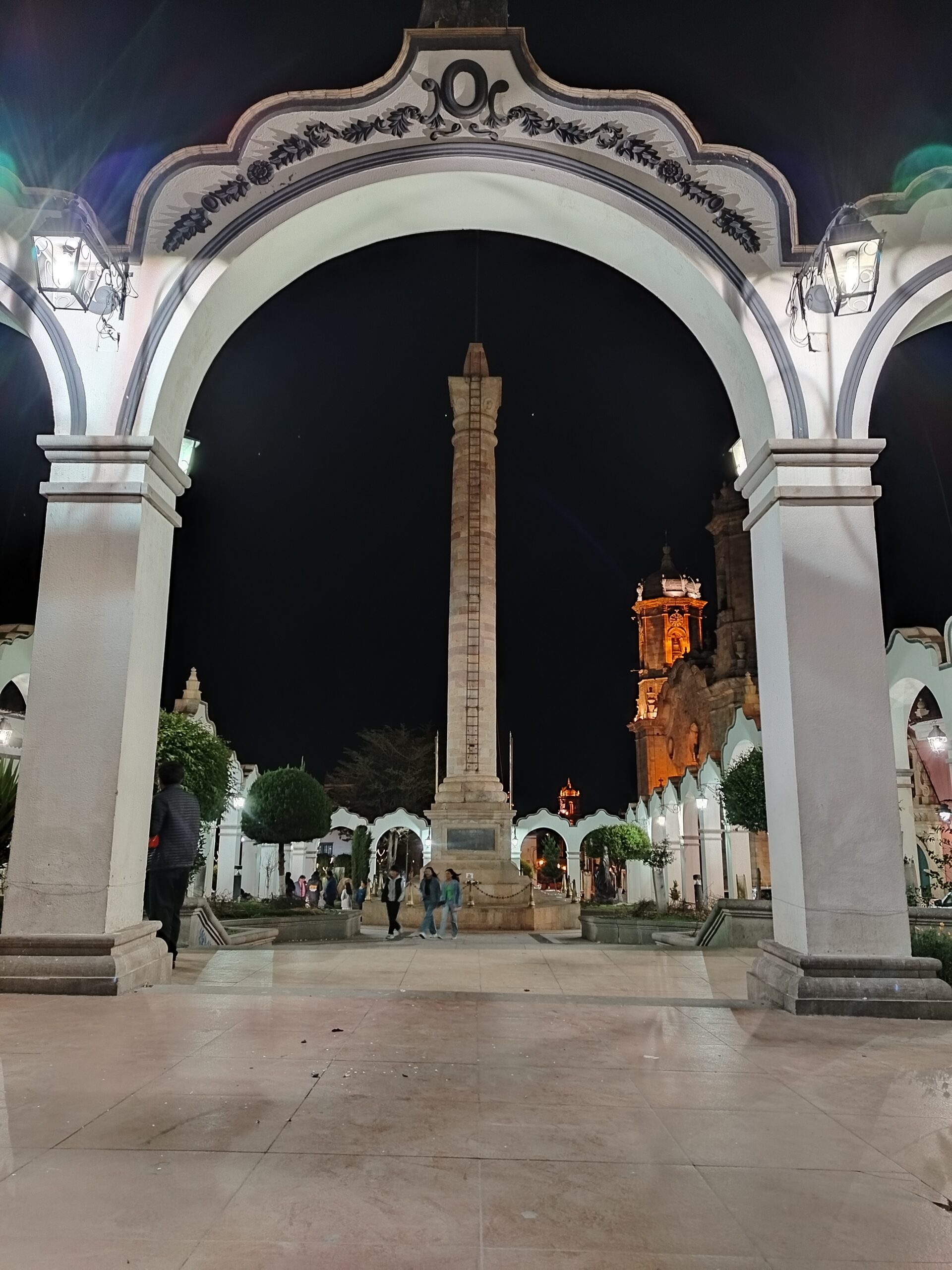 Entrada con arco de la plaza de Potosí iluminada por la noche