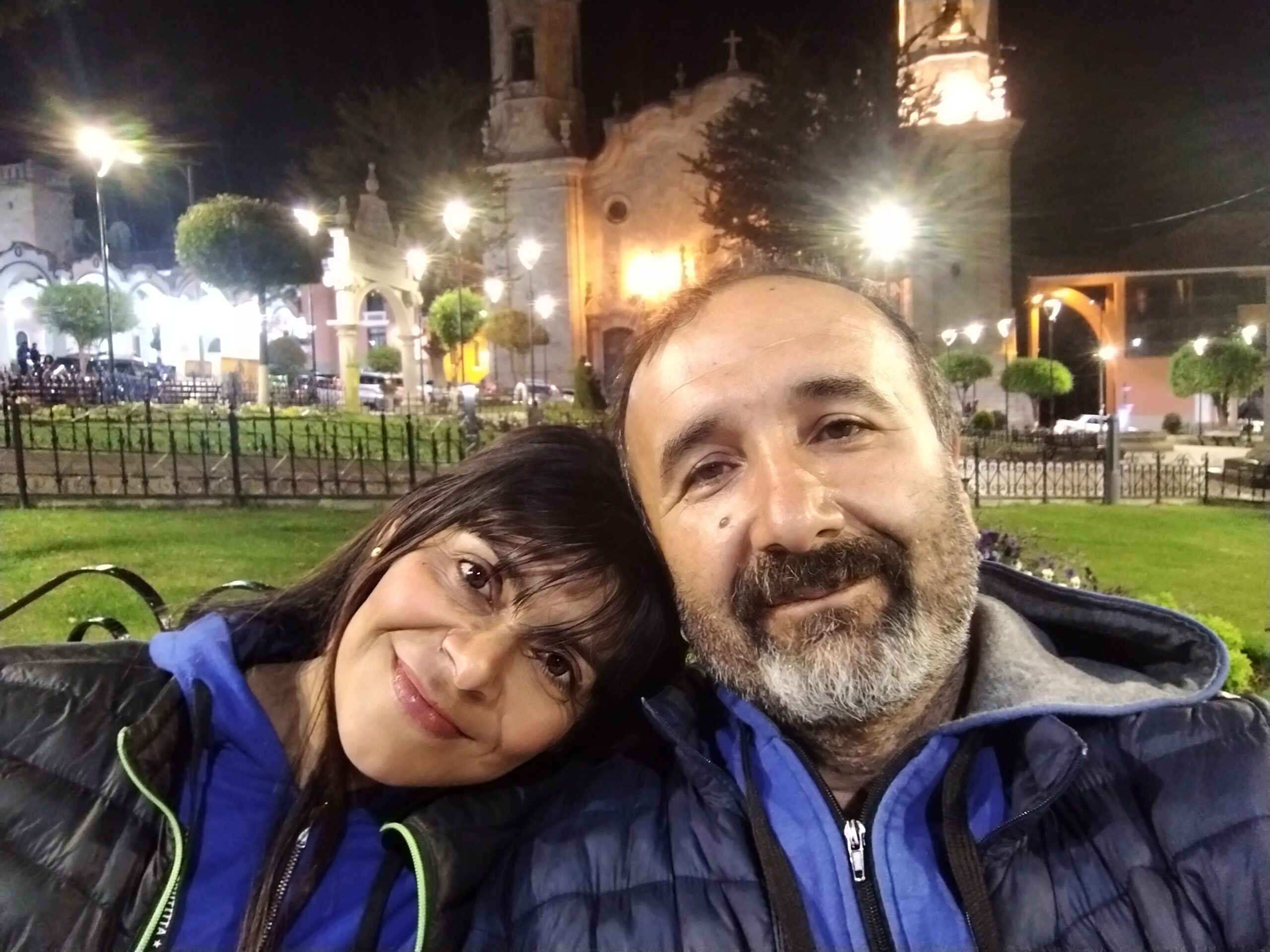 Dos viajeros descansando en la plaza iluminada de Potosí por la noche