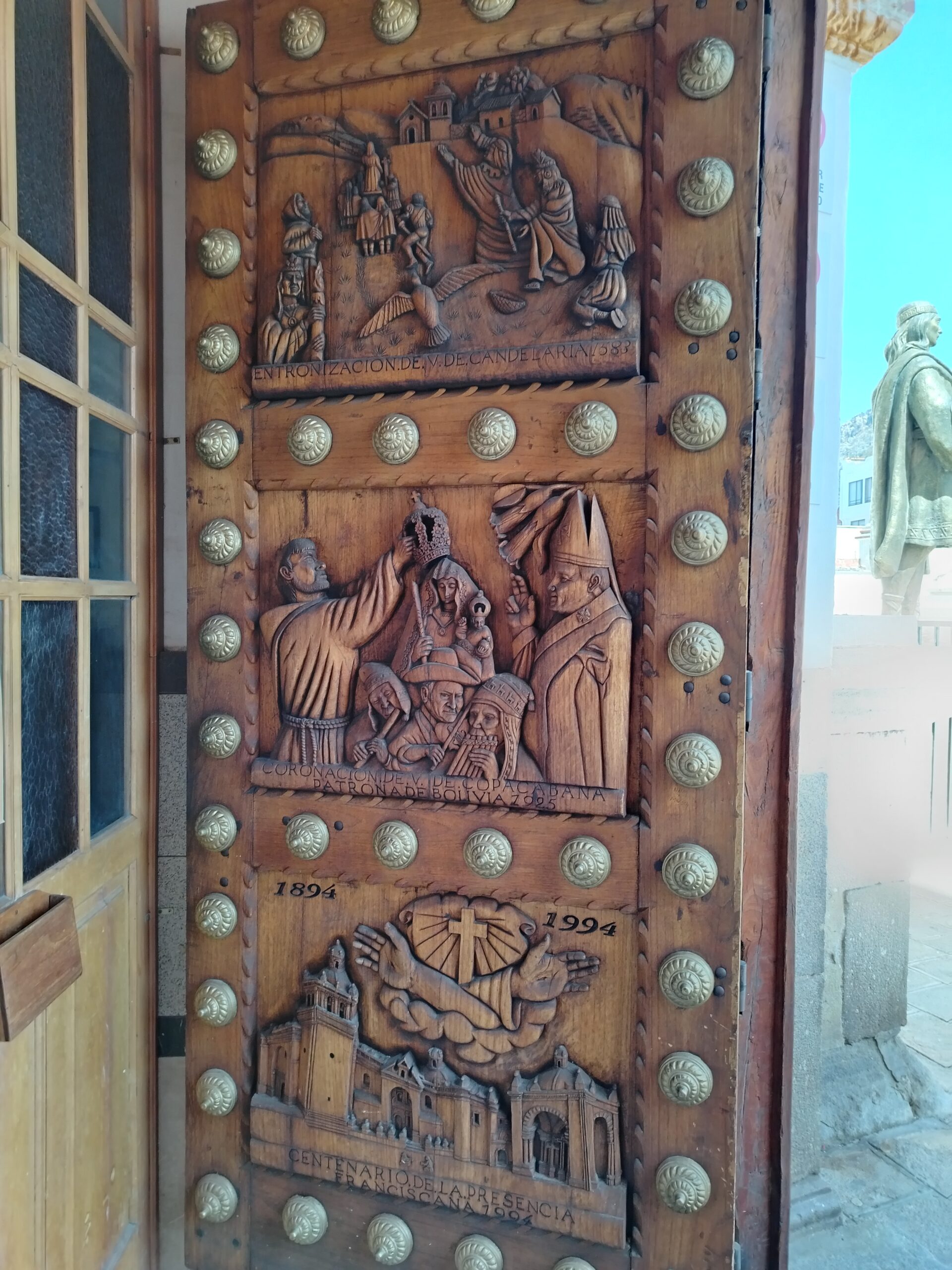 Puerta de madera tallada de la basílica de Copacabana, decorada con escenas religiosas
