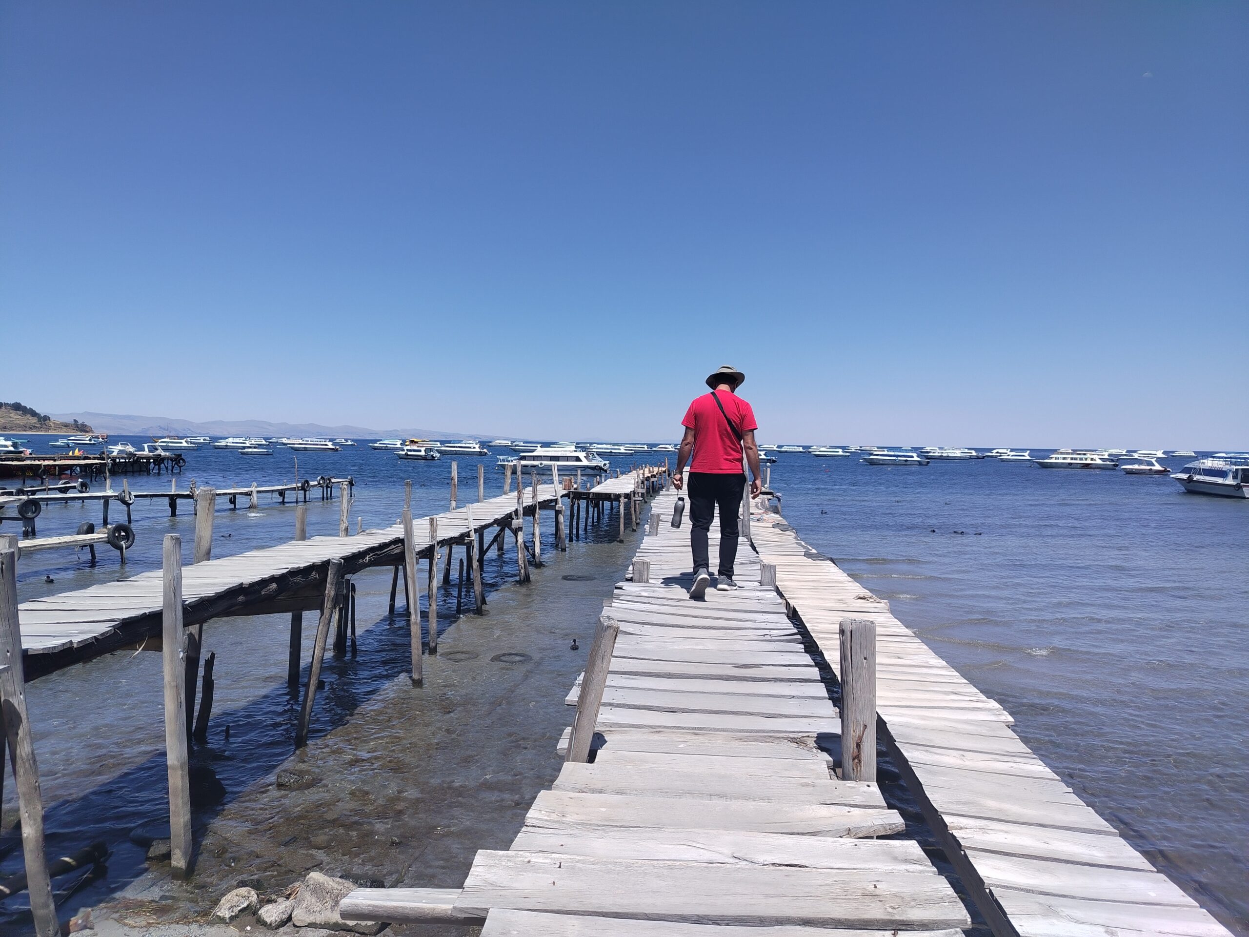 Viajero caminando por un muelle de madera sobre el lago Titicaca